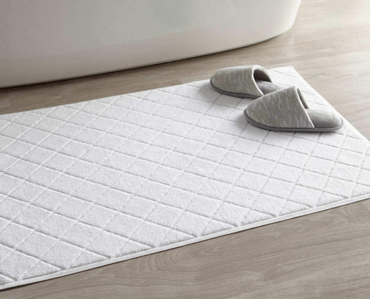white diamond sculpted bath rug in bathroom with slippers